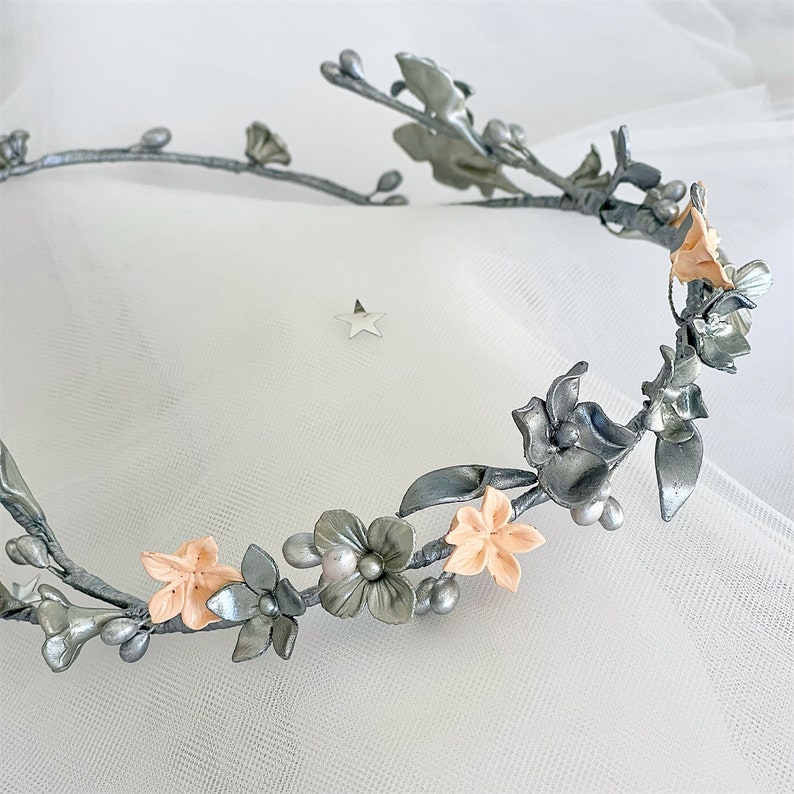 In this image we can see the wreath of flowers and porcelain leaves in silver color on a white background.