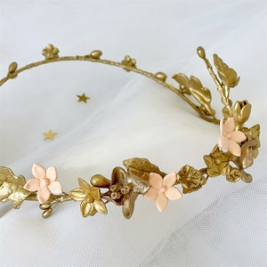 In this image we can see the wreath of flowers and porcelain leaves in golden color on a white background.