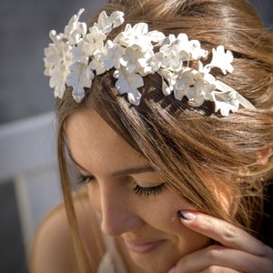 In this image we can see the bride with her handmade white porcelain flower and leaf tiara more closely in profile looking slightly downward.