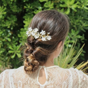 here the bride is seen from behind in a garden with the sun shining down and the porcelain flower hair piece on her head