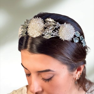 In this image we can see the bride with her bridal tiara crown with rhinestones, porcelain leaves and silver-colored crystals.