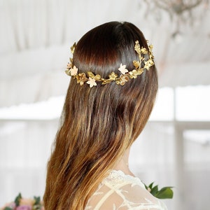 In this image we can see the bride from behind with her crown of flowers and porcelain leaves in golden color.