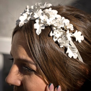 In this detail image we can see the bride with her tiara of flowers and white porcelain leaves handmade in a garden.