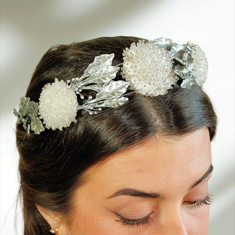 In this image we can see the bride with her bridal tiara crown with rhinestones, porcelain leaves and silver-colored crystals.