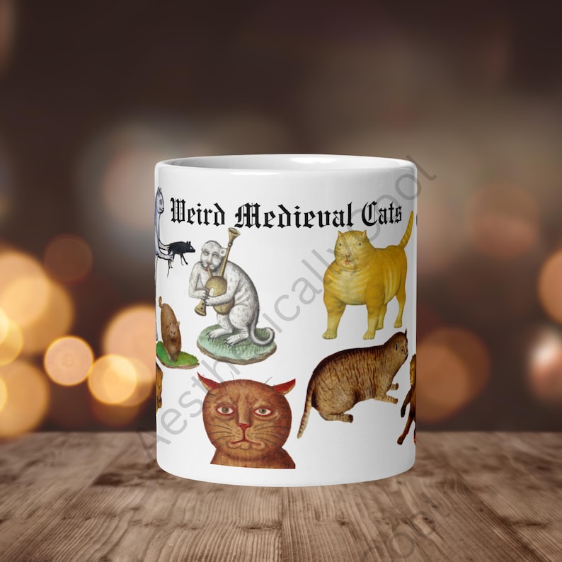 White ceramic coffee mug with full color illustrations of cats in medieval attire, engaging in humorous activities like playing instruments, holding mice, and making funny faces. Perfect gift for cat lovers with a sense of humor