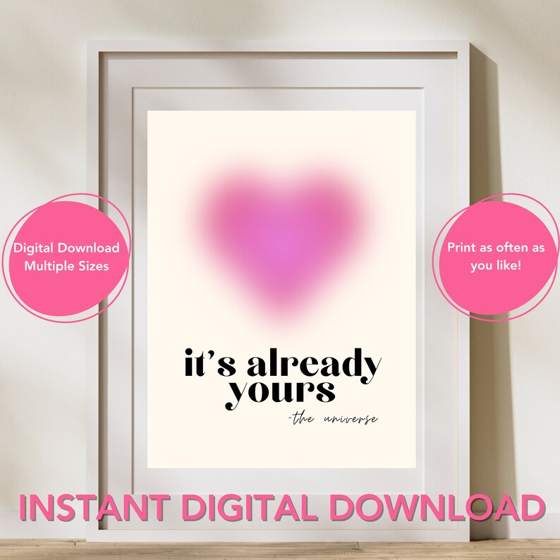 May include: A digital download of a pink heart with the text "it's already yours - the universe" in black. The image is framed in a white frame and has a pink background.