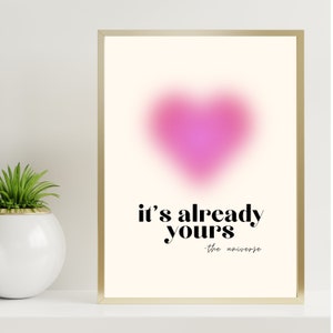 May include: A pink heart-shaped graphic with a blurred effect, with the text "it's already yours - the universe" in black.