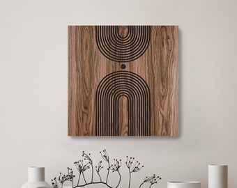 Op de afbeelding: Een houten wandkunstwerk met een geometrisch ontwerp van zwarte bogen en een cirkel op een bruine houten achtergrond.