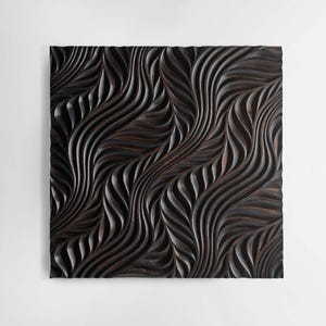 May include: A black wooden wall art piece with a carved pattern of swirling lines and curves.