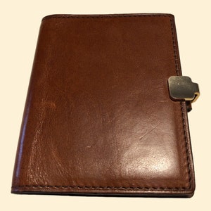 May include: A brown leather bound journal with a gold metal clasp.