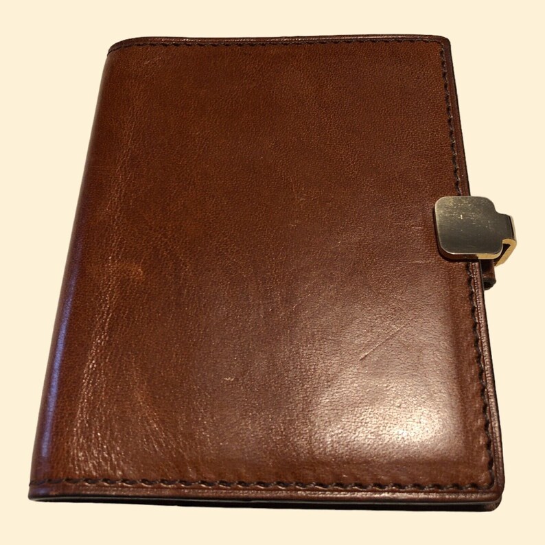 May include: A brown leather bound journal with a gold metal clasp.