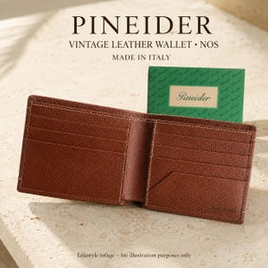May include: A brown leather bifold wallet with multiple card slots and a textured surface. The wallet is open, displaying its interior compartments. Text above reads PINEIDER VINTAGE LEATHER WALLET NOS MADE IN ITALY, with a green Pineider card.
