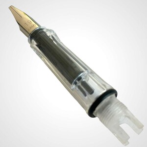May include: A clear fountain pen nib with a gold-colored tip. The nib is marked with "1.9" and "LAMY". The pen has a transparent barrel, revealing the internal ink mechanism. The pen's design is modern and sleek.