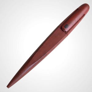 May include: A reddish-brown pen with a cap, set against a white background. The pen has a sleek, angular design with a pointed tip. The cap features a small, dark emblem. The pen appears to be made of wood or a similar material.