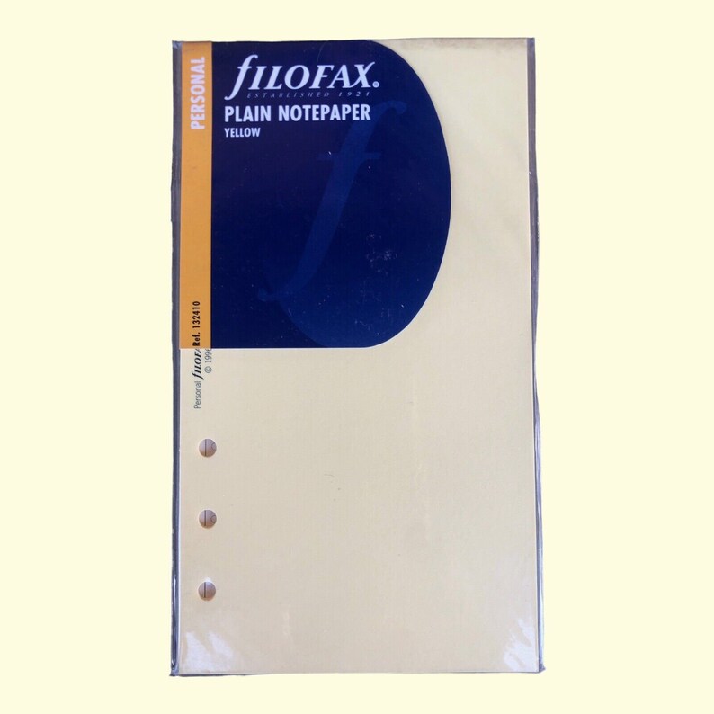Pu&ograve; includere: Un pacchetto di carta bianca gialla Filofax per un'agenda di formato personale. La confezione ha un'etichetta blu e bianca con il logo Filofax e il testo "Plain Notepaper Yellow".