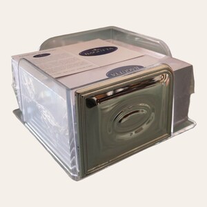 May include: A clear plastic desk organiser with a silver metal base. The organiser is filled with white notepads and has the word "Bagutta" printed on the top of the notepads.