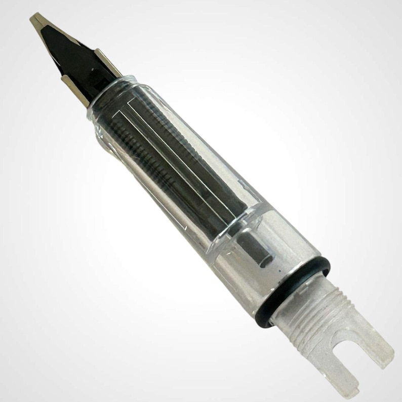 May include: A clear fountain pen with a black nib and internal ink reservoir. The pen has a transparent barrel, allowing visibility of the internal components. The nib is silver and black, and the pen has a unique, modern design.