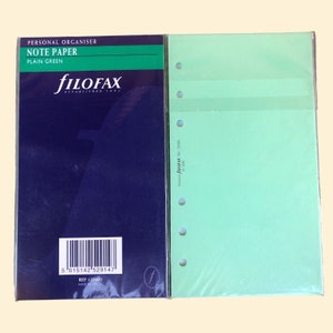 Pu&ograve; includere: Un pacchetto di carta per appunti di colore verde chiaro per un organizer personale Filofax. La confezione ha un codice a barre e il testo "PERSONAL ORGANISER NOTE PAPER PLAIN GREEN fILOFAX ESTABLISHED 1921 REF 132402 MADE IN THE UK" stampato su di essa.