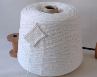 May include: A white cone of yarn with a small white knitted swatch attached to the side.