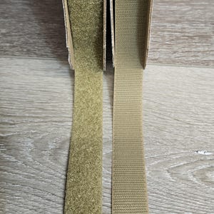 May include: Two strips of hook and loop fastener tape, one with a fuzzy texture and one with a smooth texture, both in a light brown color.