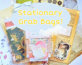 Op de afbeelding: Een verzameling verrassingstassen met briefpapier, inclusief diverse papieren artikelen zoals washi-tape met patronen, stickers en decoratieve vellen. De items zijn verpakt in doorzichtige plastic hoesjes, met de tekst Stationary Grab Bags!