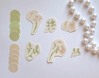 Op de afbeelding: Een set papieren ambachtelijke stickers met witte rozen, groene bladeren en cirkels in beige en groen. De stickers zijn perfect om een ​​toets van elegantie toe te voegen aan dagboeken, planners en andere knutselprojecten.