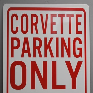 May include: Red and white sign with the text "Corvette Parking Only" and a red arrow pointing to the left and right. The text "All Others Will Be Towed" is below the arrow.
