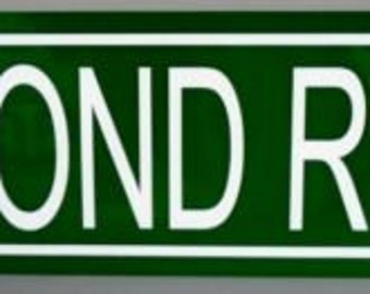 Op de afbeelding: Een rechthoekig groen straatnaambord met een witte rand en witte letters met de tekst DIAMOND REO AVE. Het bord heeft afgeronde hoeken en een strak, contrastrijk ontwerp dat typerend is voor standaard straatnaamborden.