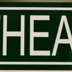 Puede incluir: Un letrero de calle rectangular verde con texto blanco "FLATHEAD DRIVE". El letrero tiene un borde blanco y se utiliza para la identificación de calles.