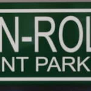 Puede incluir: Un letrero verde con letras blancas que dice "Rock-N-Roll H.S. Student Parking" con una flecha blanca apuntando hacia la derecha.