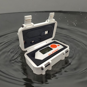May include: A white waterproof case with a black interior and a small white device with an orange button and the word "FLIPPER" printed on it. The case is open and the device is inside.