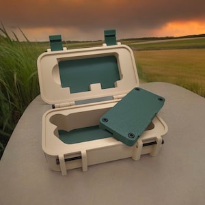 May include: A small, beige, rectangular box with a green lid and a green insert. The box is open and the insert is partially removed. The box is sitting on a beige surface.