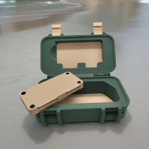 Peut inclure: Une boîte étanche verte avec un insert en mousse beige. La boîte est ouverte et l'insert est partiellement retiré.