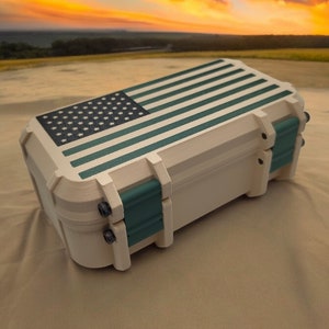 May include: A beige hard plastic case with a green and black American flag design. The case has a latch and hinges.