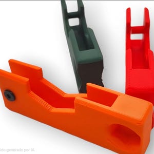 May include: Three 3D-printed objects in orange, green, and red. The orange object is in the foreground, with a rectangular shape and a small black screw. The green and red objects are in the background, with a similar design.