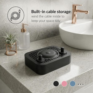 Puede incluir: Un organizador de cables negro con una parte superior circular y dos postes pequeños. El dispositivo es rectangular con una parte superior en forma de rejilla. El texto dice "Built-in cable storage: wind the cable inside to keep your space tidy."
