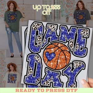 May include: A graphic design featuring the words "GAME DAY" in blue glitter and leopard print, with an orange basketball and a blue heart. The design is ready to press on a DTF transfer.