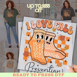 May include: A graphic design featuring the text "I LOVE FALL" in orange and peach tones, with two cartoon socks. The socks have smiling faces and are set against a checkered orange and white background. The words "Prevention" and "READY TO PRESS DTF" are also visible.