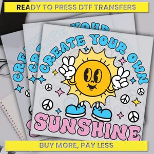 May include: DTF transfers with a retro sun graphic that says "Create Your Own Sunshine." The sun is yellow with a smiling face, peace signs, and blue shoes. The text "Ready to Press DTF Transfers" is at the top.