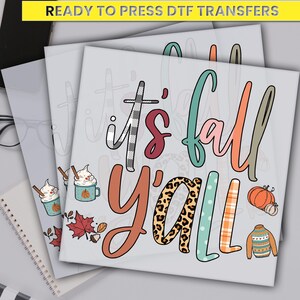 May include: DTF transfer with the text "It's Fall Y'all" in a variety of fonts and colors. The design includes fall-themed illustrations such as pumpkins, a sweater, and coffee mugs. The words are in a mix of fonts and patterns.