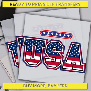 May include: DTF transfers featuring the word "USA" in a bold, collegiate-style font. The letters are filled with a blue starry pattern and red and white stripes, outlined in black and blue. The image includes the text "READY TO PRESS DTF TRANSFERS" and "BUY MORE, PAY LESS".