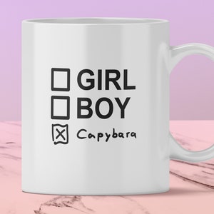 Może przedstawiać: Biały kubek ceramiczny z czarnym polem wyboru i tekstem "GIRL" i "BOY" z zaznaczeniem obok tekstu "Capybara".
