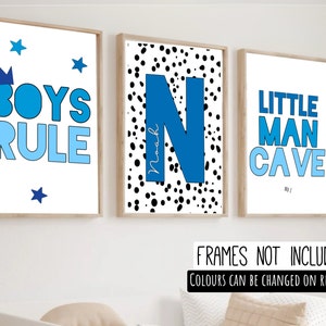 May include: Three framed prints with blue and white designs. The first print says "Boys Rule" with a crown and stars. The second print has a large blue "N" with black polka dots. The third print says "Little Man Cave" with a blue and white design.