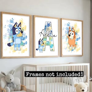 May include: Three framed prints with watercolor backgrounds and cartoon dog characters. The first print features a blue dog with a yellow and blue background. The second print features a blue dog with a yellow and blue background and the letter A with the name Albie. The third print features an orange dog with a yellow and blue background.