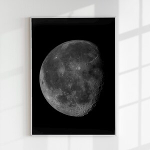 May include: A black and white photograph of the moon in a crescent phase, showing the surface details of the moon against a black background.