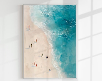 May include: A framed art print depicting a beach scene from an aerial perspective. The artwork features a sandy shore, turquoise ocean water, and small figures of people. The print is displayed against a white wall with shadows.