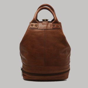 Peut inclure: Un sac à dos en cuir marron avec deux compartiments zippés et une poignée supérieure.