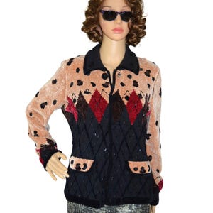 May include: A vintage button-up jacket with a unique design. The jacket features a peach-colored upper with black spots and a black collar. The lower portion is black with a diamond pattern, red and brown accents, and two pockets.
