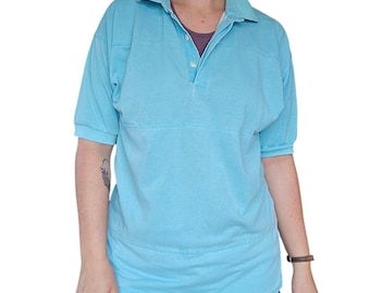Puede incluir: Un polo de manga corta en color azul claro con cuello clásico, tapeta parcial con dos botones blancos y un detalle de costura horizontal en el pecho y la parte inferior del torso, confeccionado en tejido de algodón de color sólido.