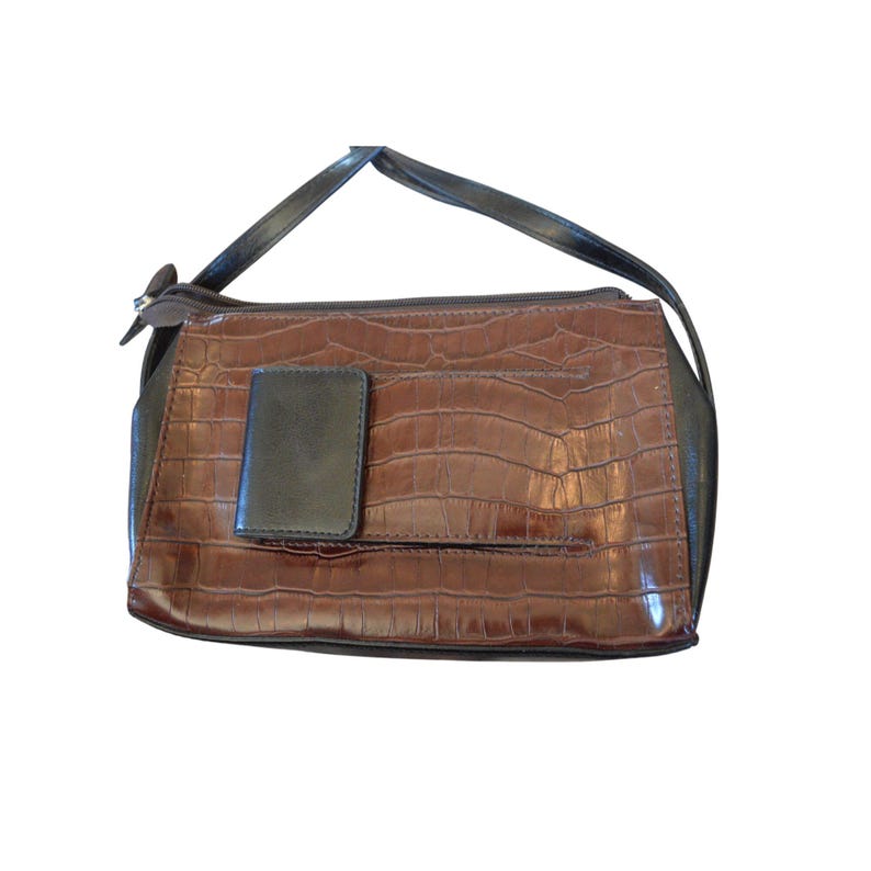 May include: A brown handbag with a crocodile skin texture. The bag has a black handle and a small black flap on the front. The bag has a zipper closure.